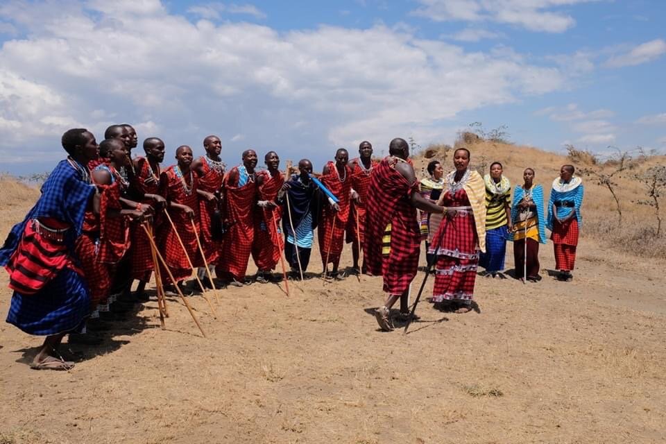 Maasai group in red shukas singing on a dry hillside near Mikumi