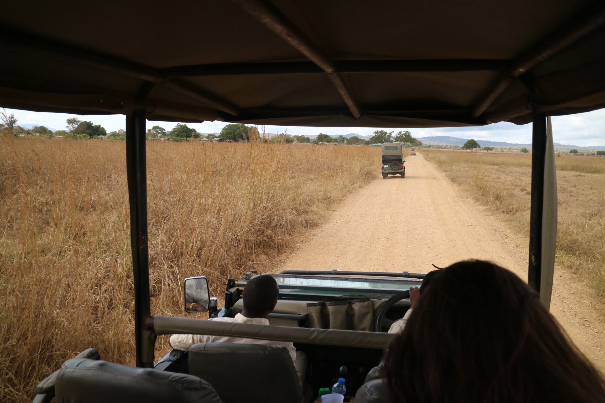 View from a safari vehicle following another along a dirt track in Mikumi National Park